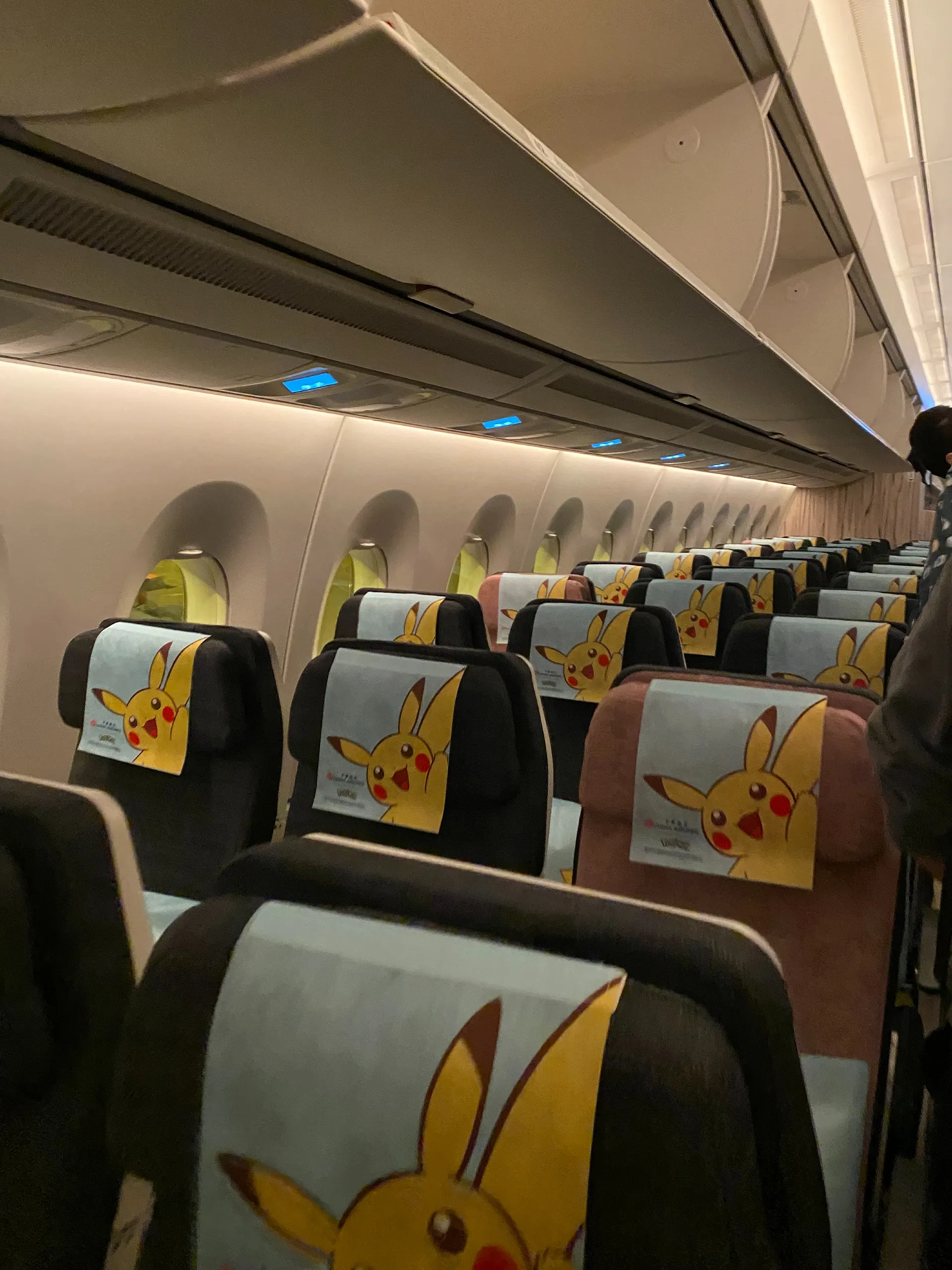 The interior of a Pokémon-themed airplane cabin with Pikachu headrest covers exudes a playful atmosphere.
