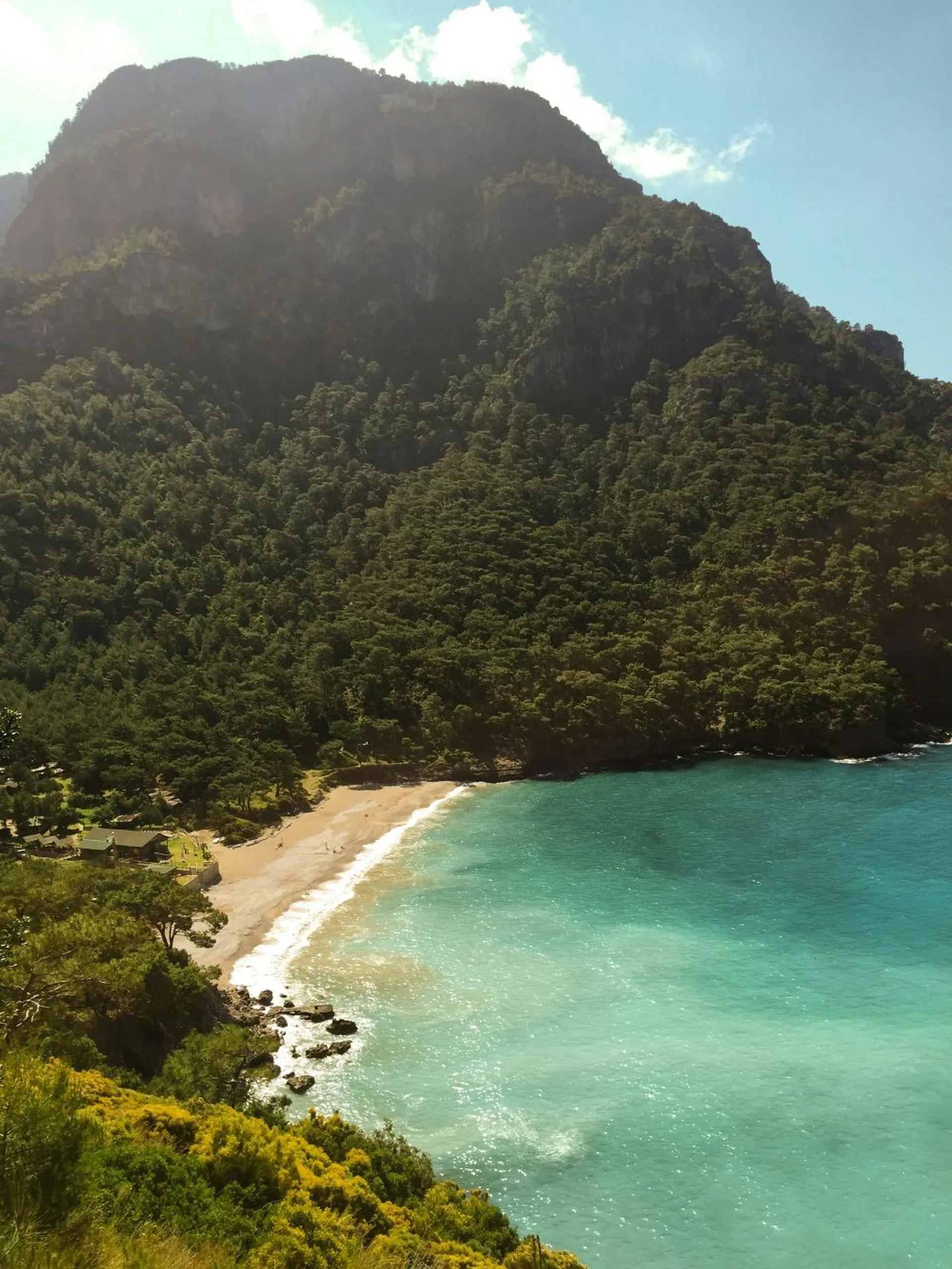 A stunning view of Kabak Bay in Turkey, featuring turquoise waters bordered by lush green hillsides.